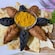 Culurgiones placed in a circle on top of pita chips with a bowl of yellow seasoning in the center